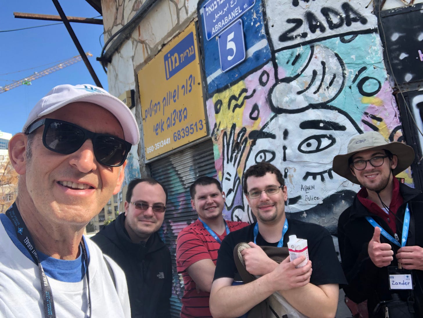 trip participants in front of a wall of grafitto in Tel Aviv
