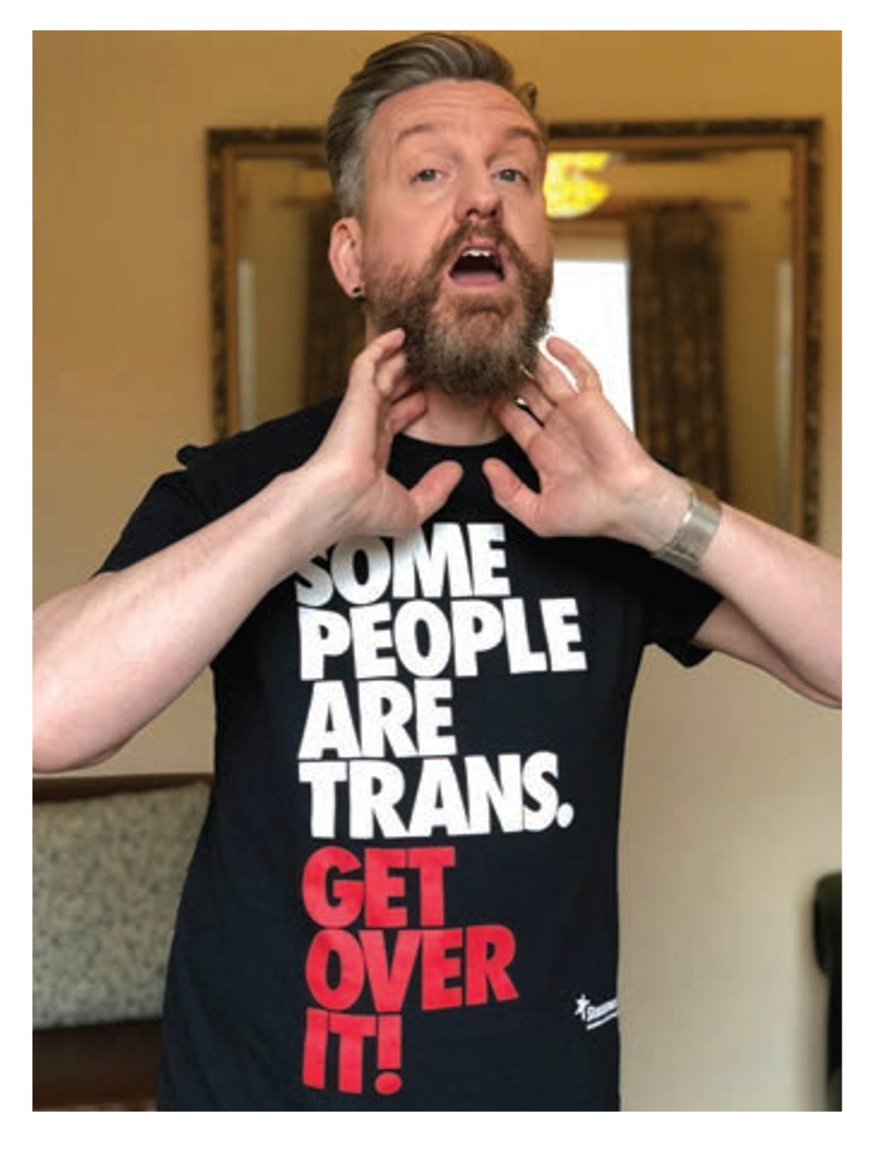Sean Pert, new chair of RCSLT, wearing a Stonewall tshirt that says Some People are Trans Get Over It and demonstrating a voice manouevre