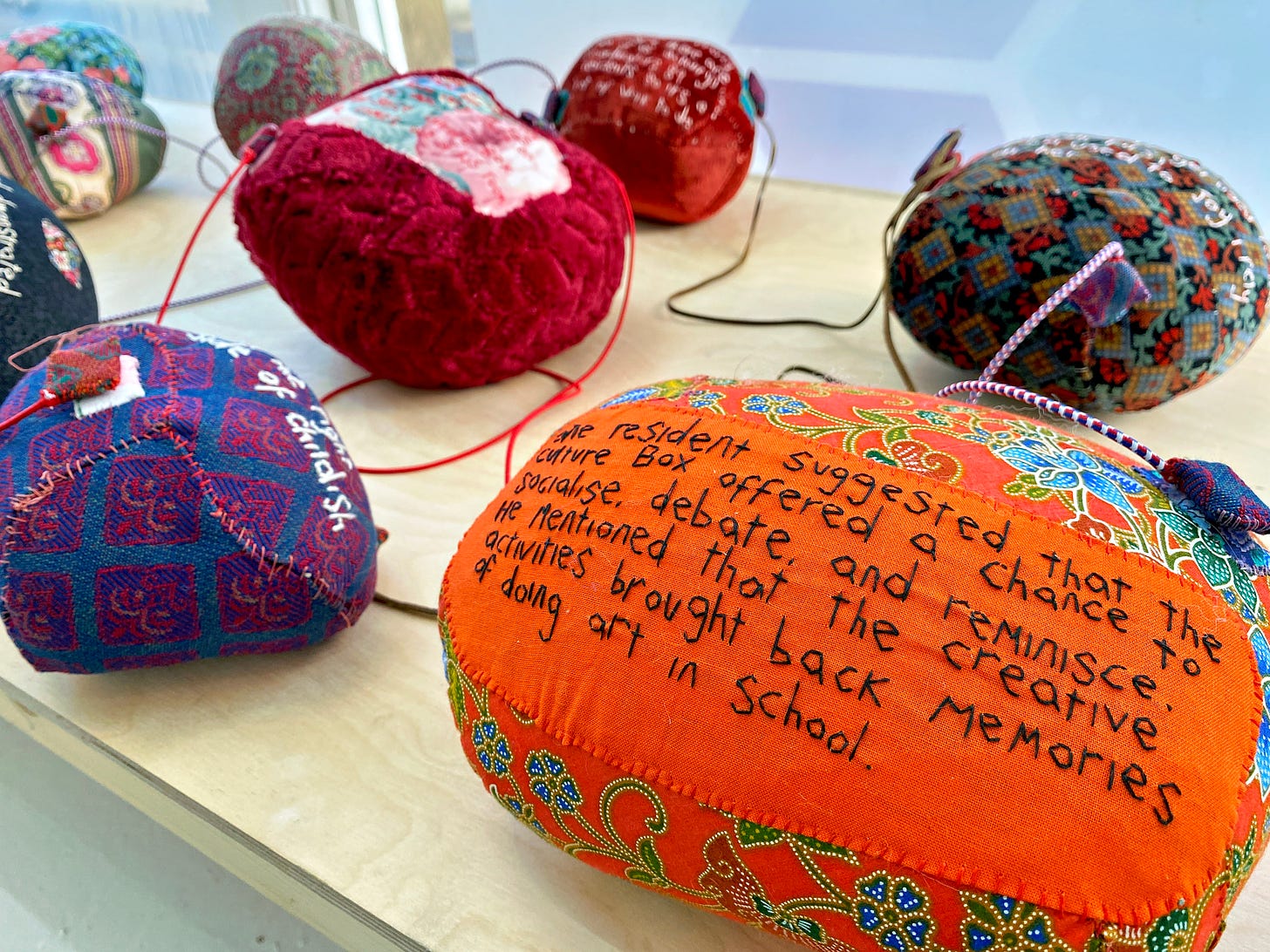 Words embroidered on small cushions reflect feedback from participants of the Culture Box project.