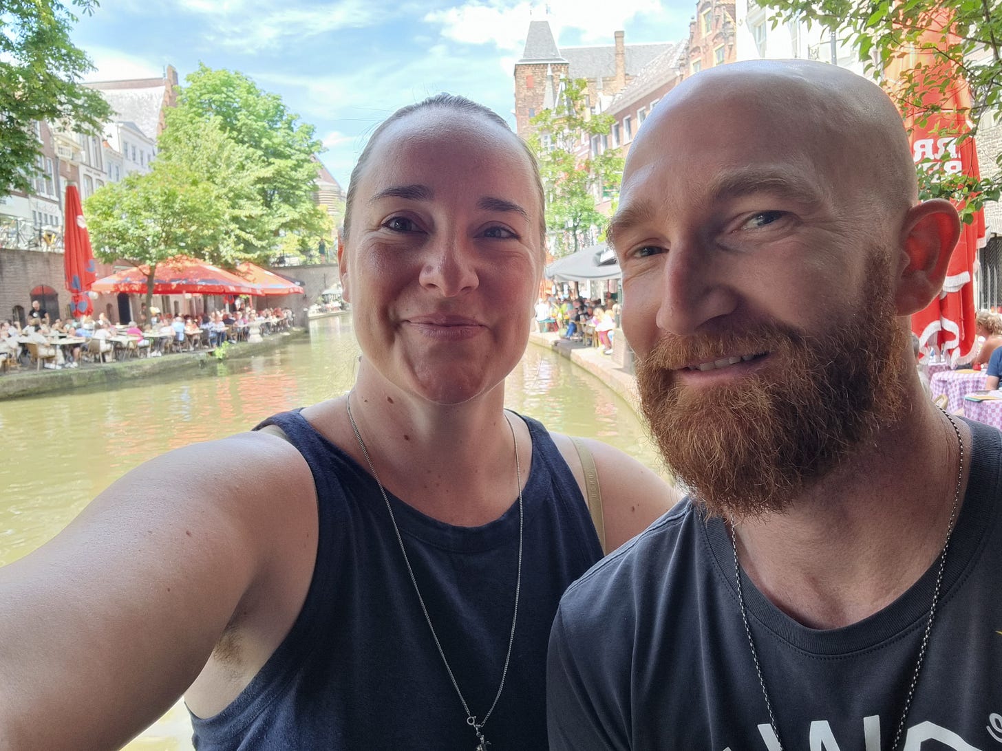 Photo of Aisling and Dave smiling at the camera while sitting next to a canal.