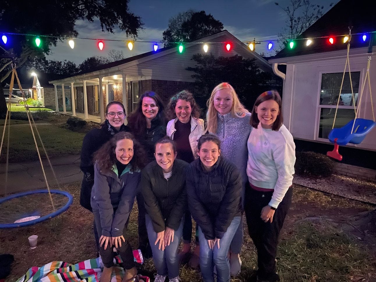 A group of women posing for a picture together in a front yard A group of women posing for a picture together in a front yard