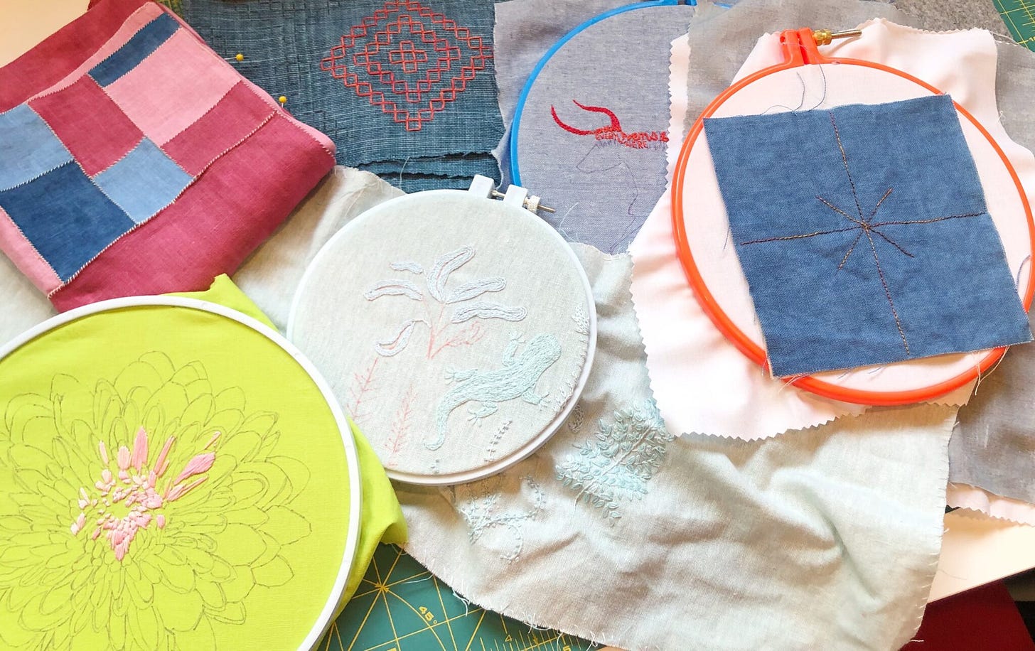 several in-progress embroidery projects jumbled on a cutting table