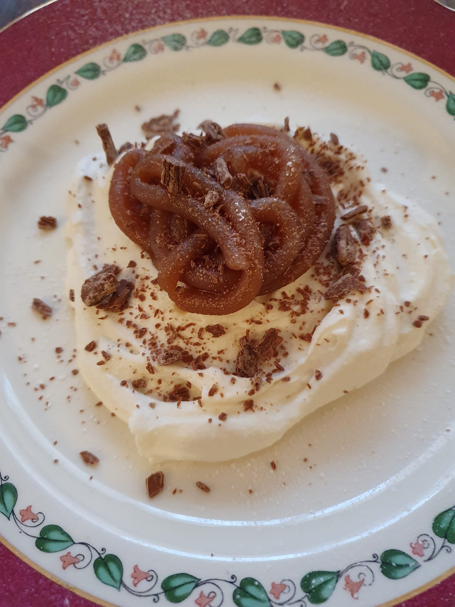 A close up of whipped cream topped with piped chestnut cream, icing sugar, and flaked milk chocolate