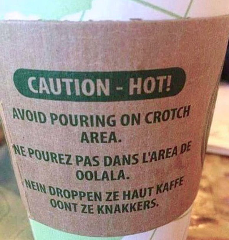 A close-up of a coffee cup with a warning in three languages. The first says avoid pouring on crotch area and the second is some kind of French talking about Ooh La, La and the third is German mentioning the knackers.