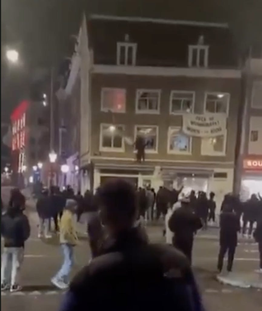 A crowd of Israelis tear down a Palestinian flag hanging on a building in the city of Amsterdam. Hundreds of Israelis and fans of the notoriously racist Maccabi Tel Aviv soccer team had traveled to the city for a match in the city. Following a string of attacks and vandalism carried out by Israelis, the Maccabi fans were targeted in what the media dubbed an 'antisemitic pogrom'. (Screenshot, X)