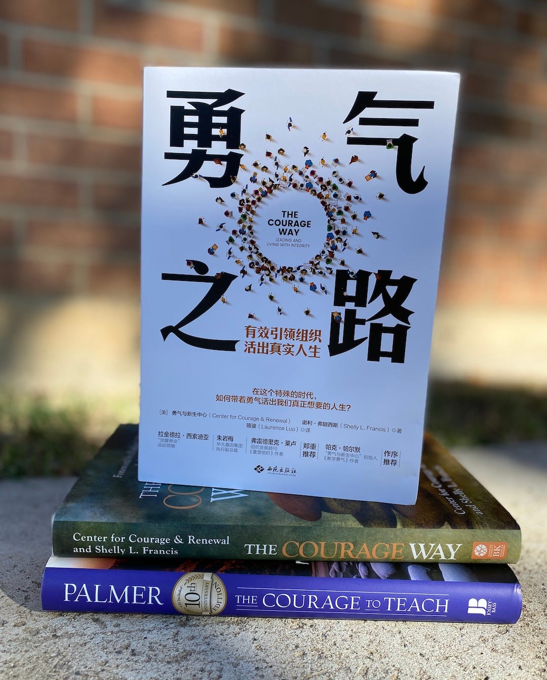 The cover of the Chinese edition of The Courage Way book sitting atop The Courage Way and The Courage to Teach books, shown spine out.