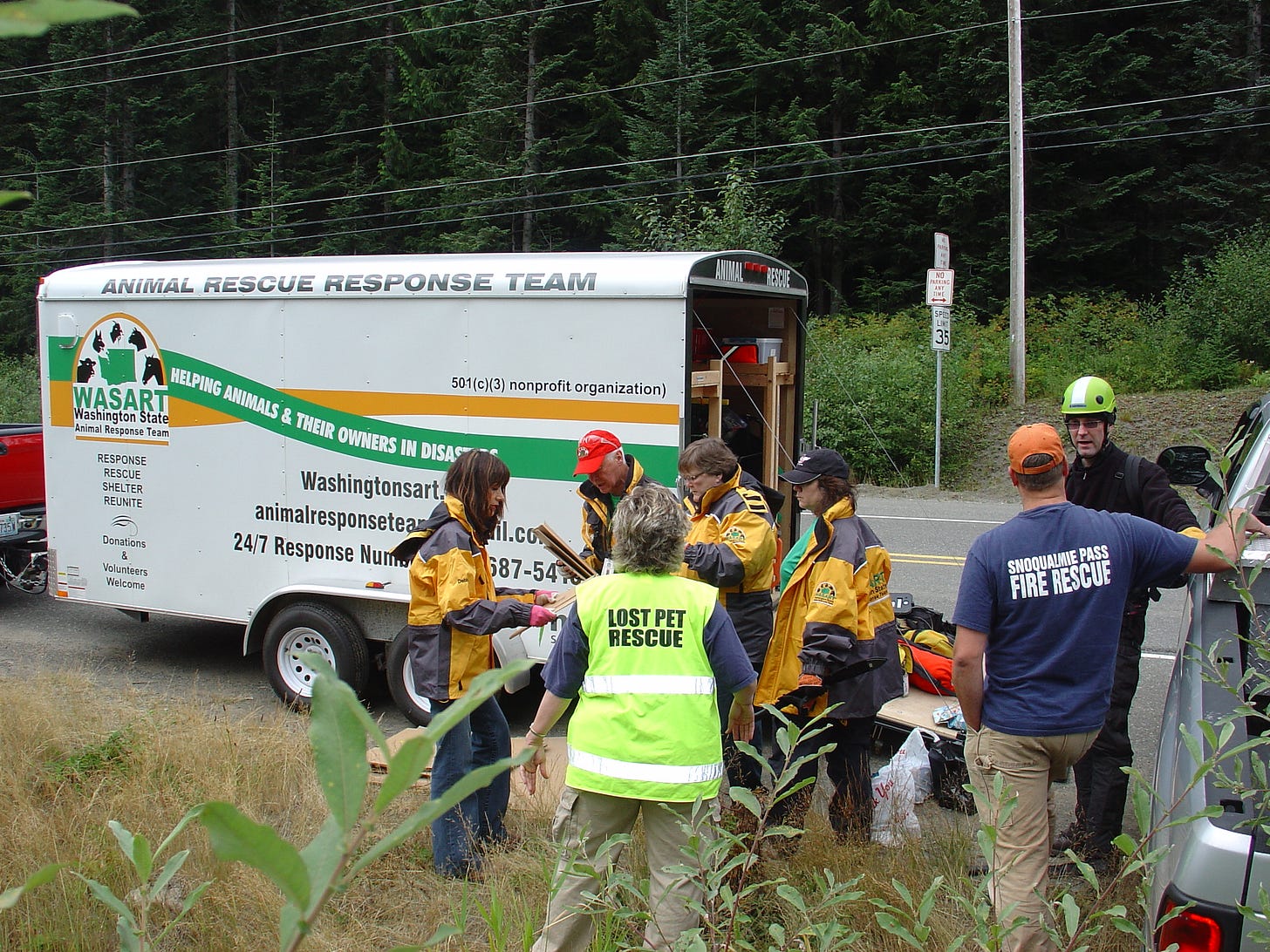 Group of rescuers, author in a green LOST PET RESCUE vest, stand around an "Animal Rescue Response Trailer" Group of rescuers, author in a green LOST PET RESCUE vest, stand around an "Animal Rescue Response Trailer"