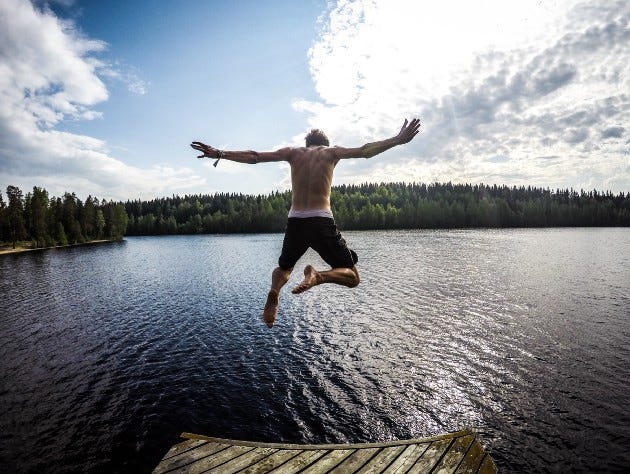 A man jumping in the water under the blue cloudy sky