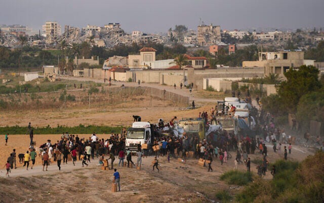 Palestinians are seen storming trucks loaded with humanitarian aid brought in through a new US-built pier, in the central Gaza Strip, on May 18, 2024. (AP Photo/Abdel Kareem Hana, File)