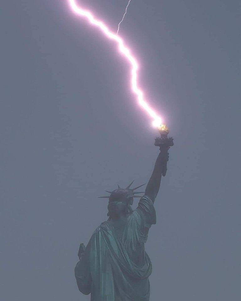 May be an image of lightning and the Statue of Liberty