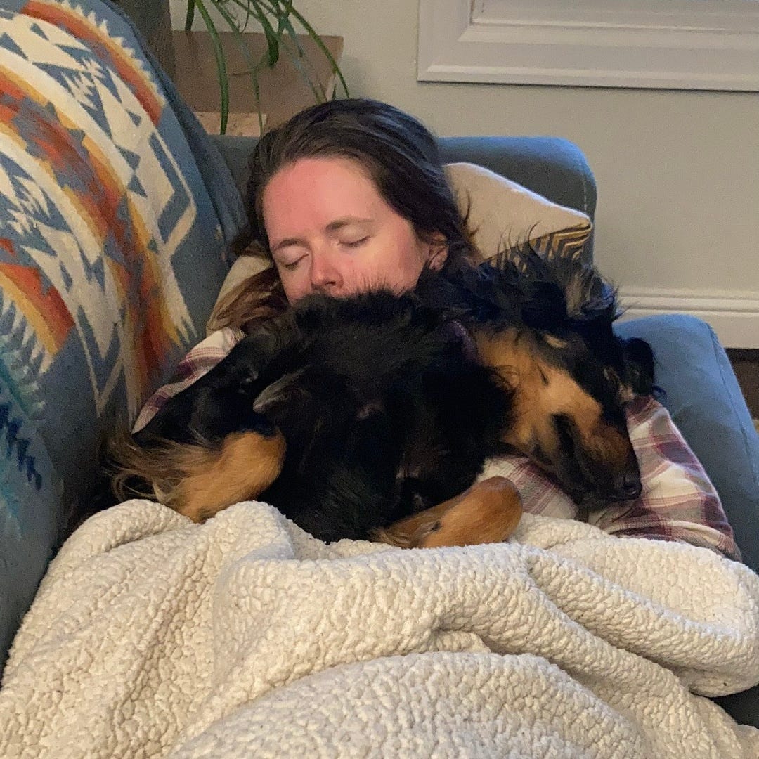 Woman sleeping on couch with dog sleeping on her