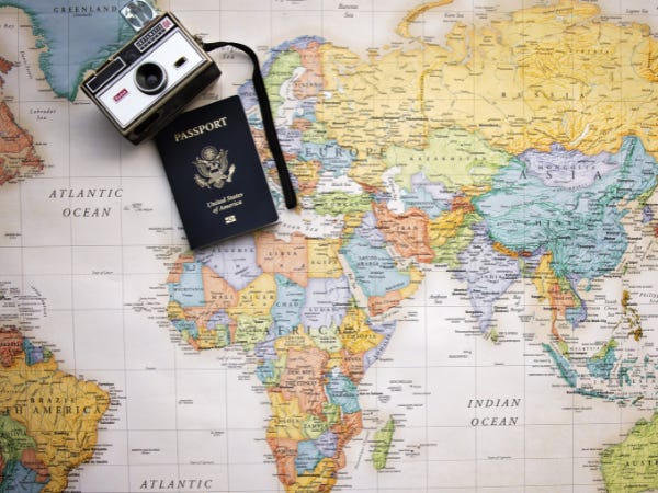 A vintage camera and passport sitting on top of a map of the world