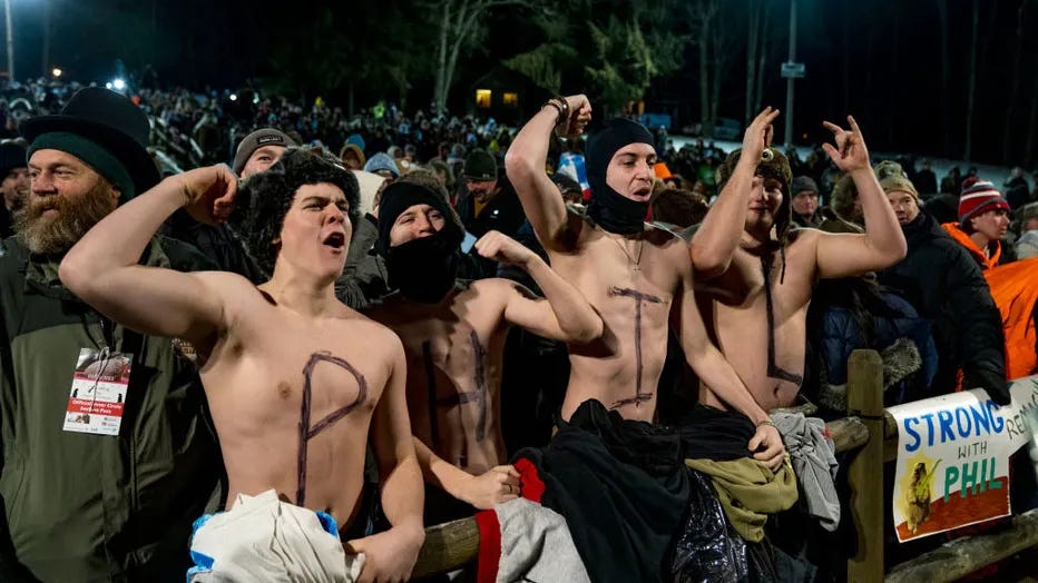 In an outdoor crowd, four college-aged idiots with their shirts off and the letters P H I L spelled on their chests.