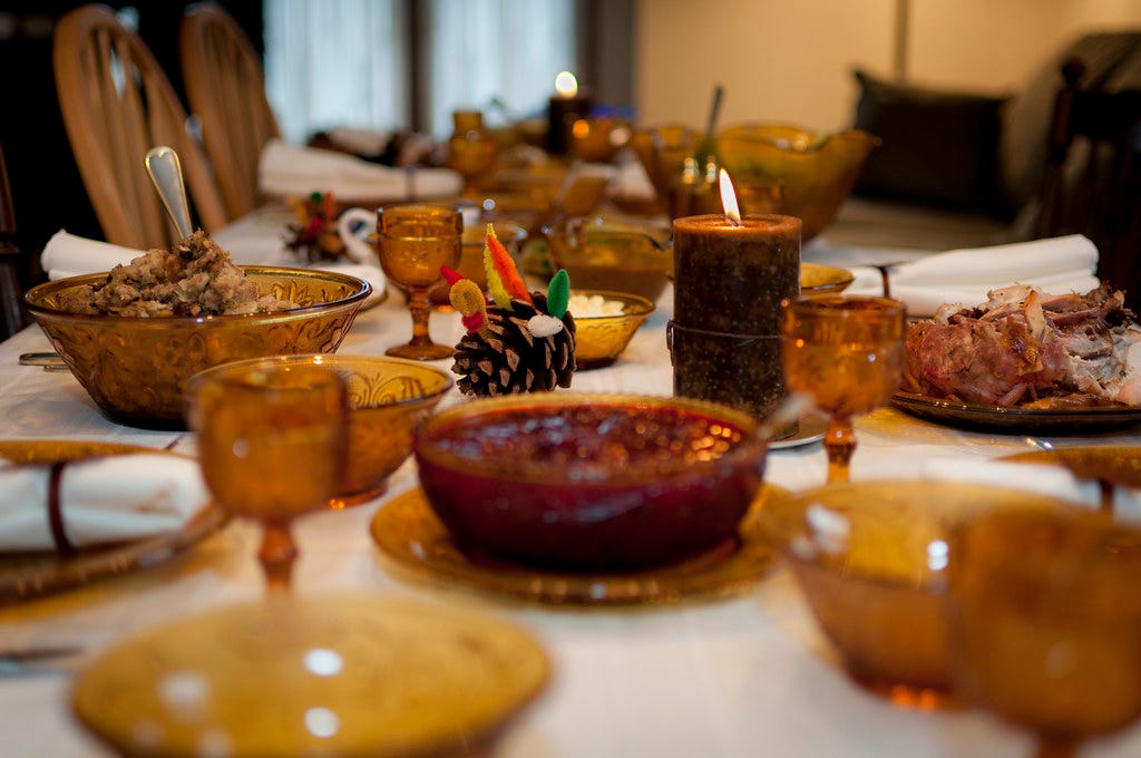 a close up of a Thanksgiving table with glasses and food. "Thanksgiving Table" by vxla is licensed under CC BY 2.0.