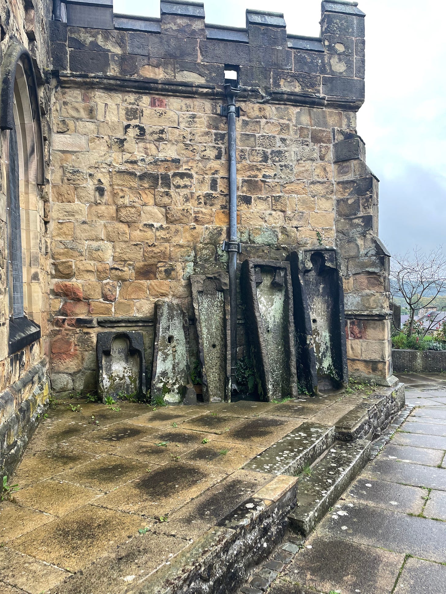 Stone coffins stand against an old church wall.