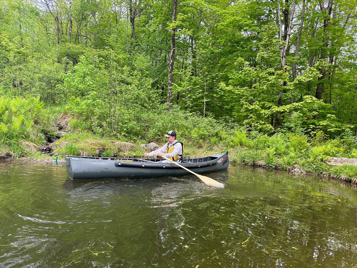 Jesse McEntee using the oar locks of the Radisson canoe on a pond to row the canoe.