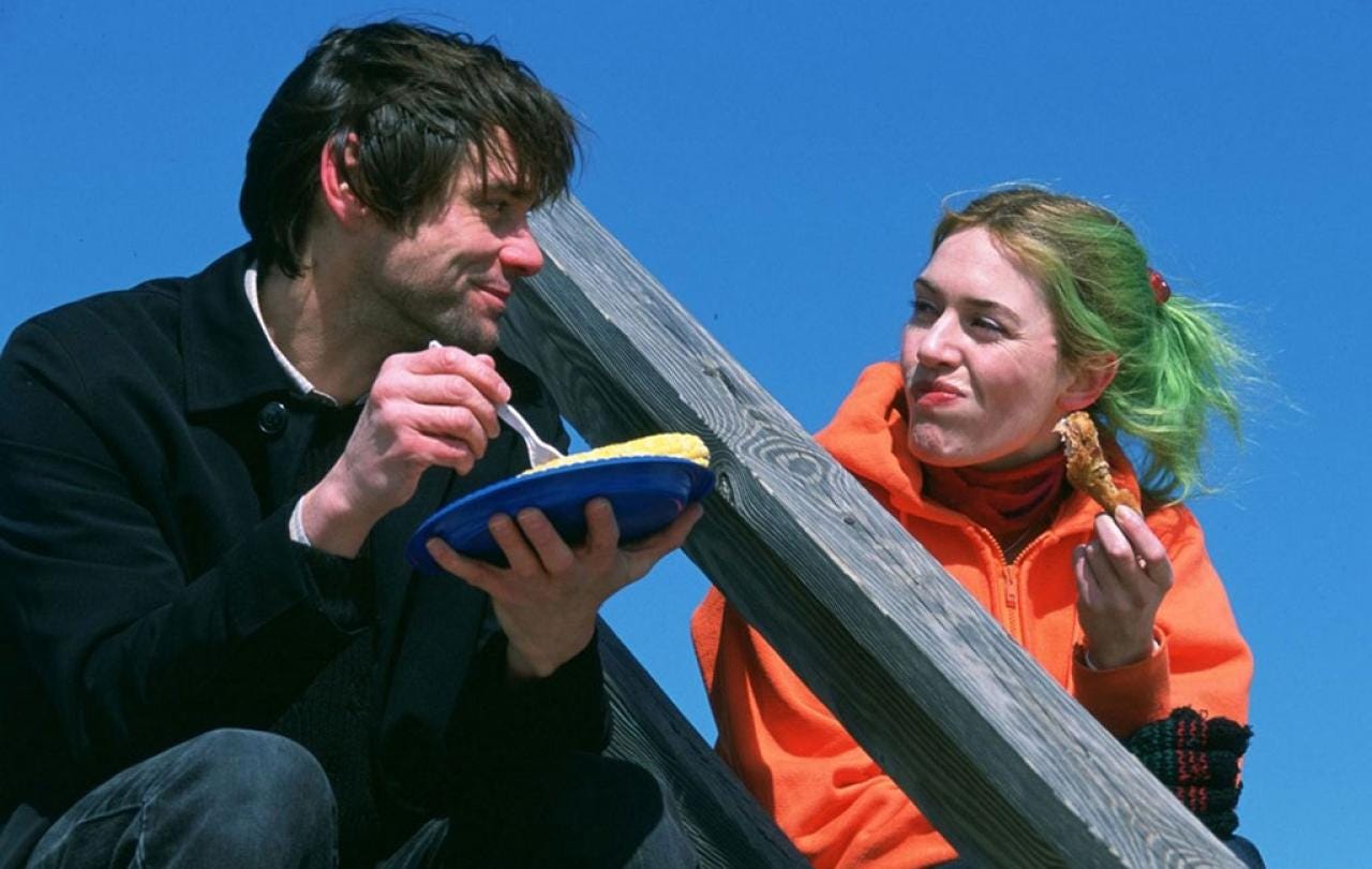 A coupe sit on outdoor steps against a blue sky. One holds a plate and the other looks towards them.