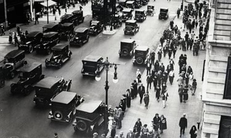 May be a black-and-white image of car, street and crowd