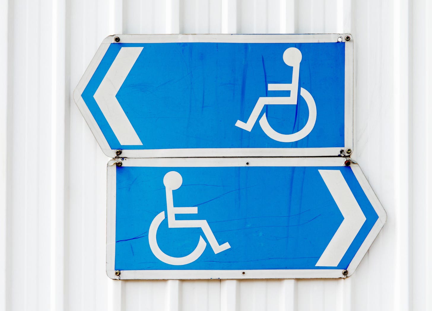 Two wheelchair symbol signed with arrows pointing in opposite directions