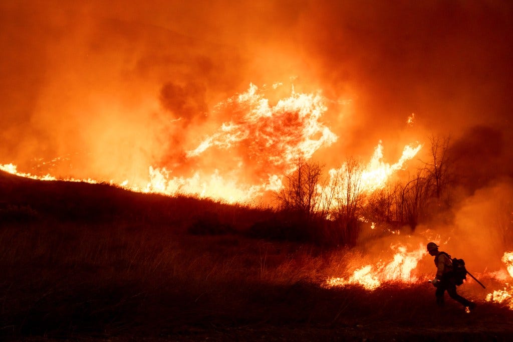 A firefighter sets a backburn in front of the advancing Kenneth Fire in the West Hills section of Los Angeles, 