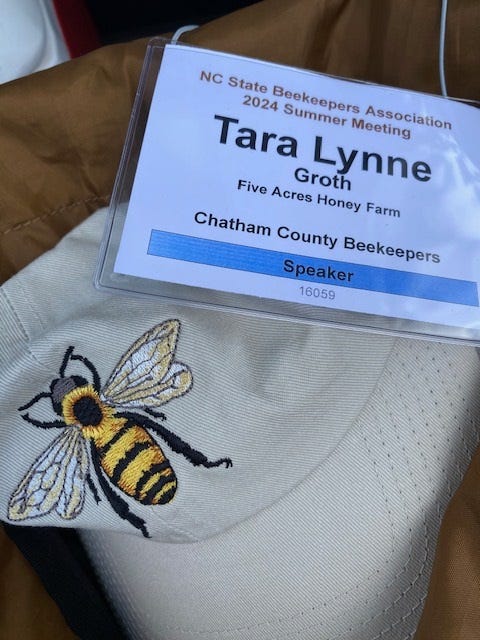 beekeeping conference speaker name tag next to a hat with queen bee embroidery