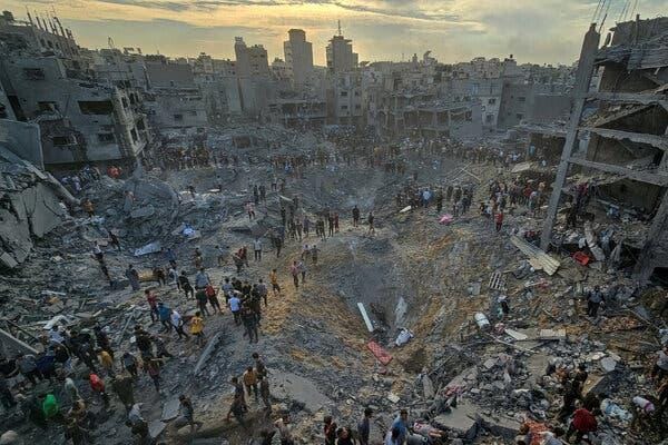 An aerial view of people searching among rubble in a heavily damaged area. 