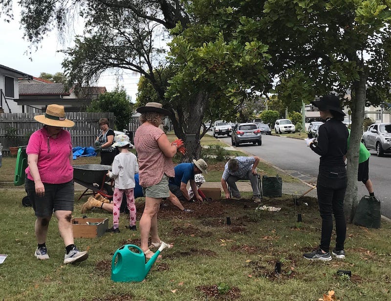 photo of people standing, sitting and kneeling as they create a verge garden