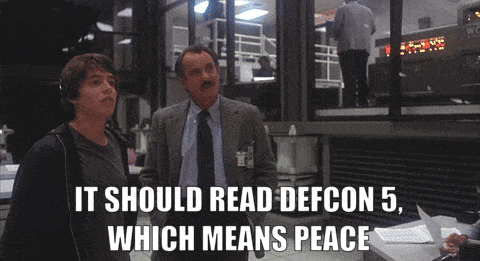 Animated GIF from WarGames. Dabney Coleman points to the DEFCON sign with 5 lit and says to Matthew Broderick, "It should read DEFCON 5, which means peace."
