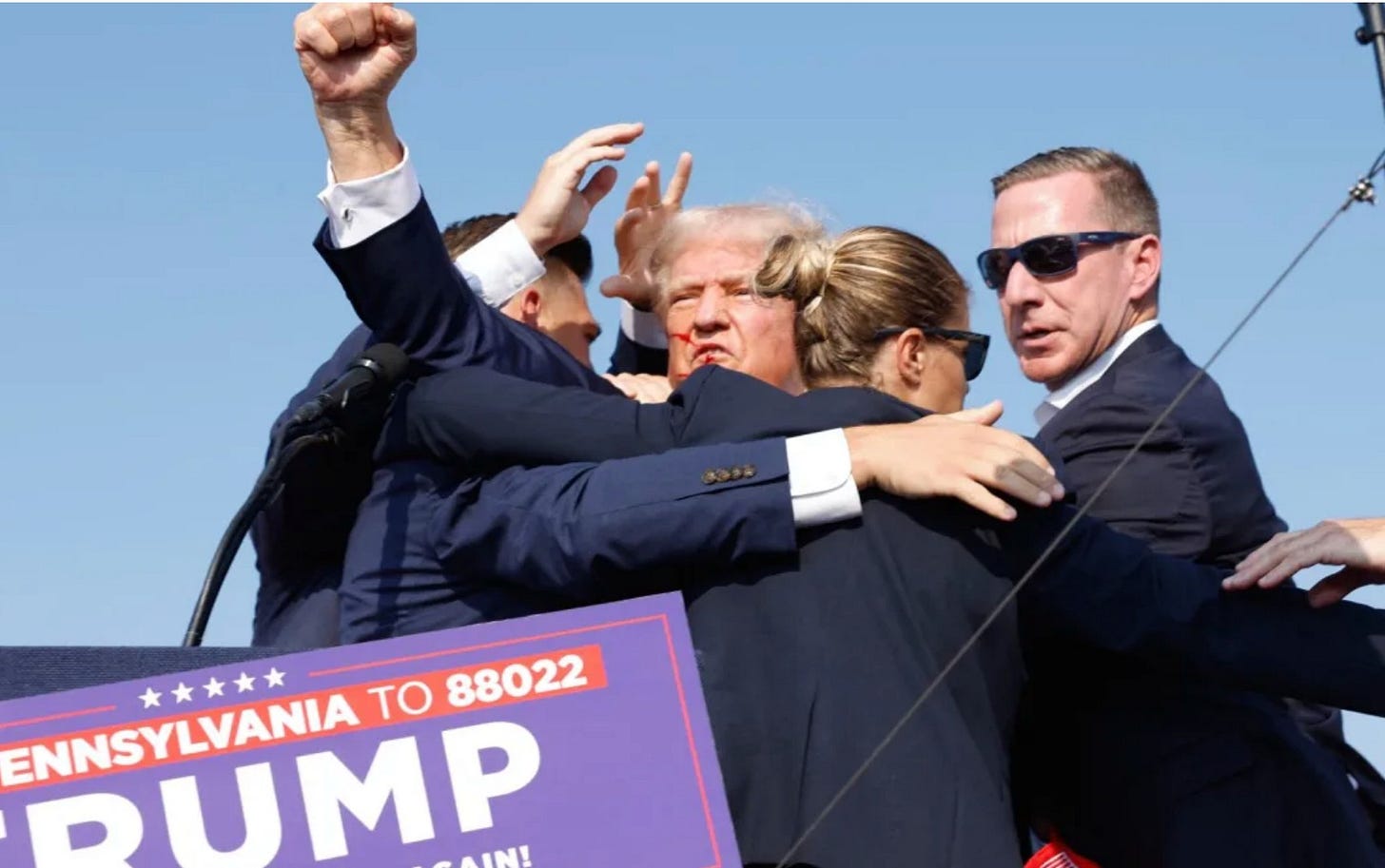 The huddle of security around Trump who punches the air.