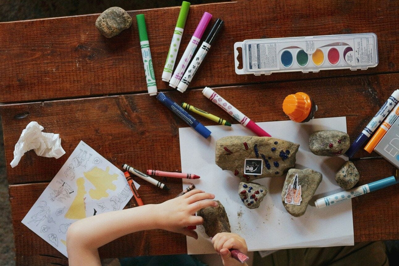 a boy with art supplies painting rocks a boy with art supplies painting rocks