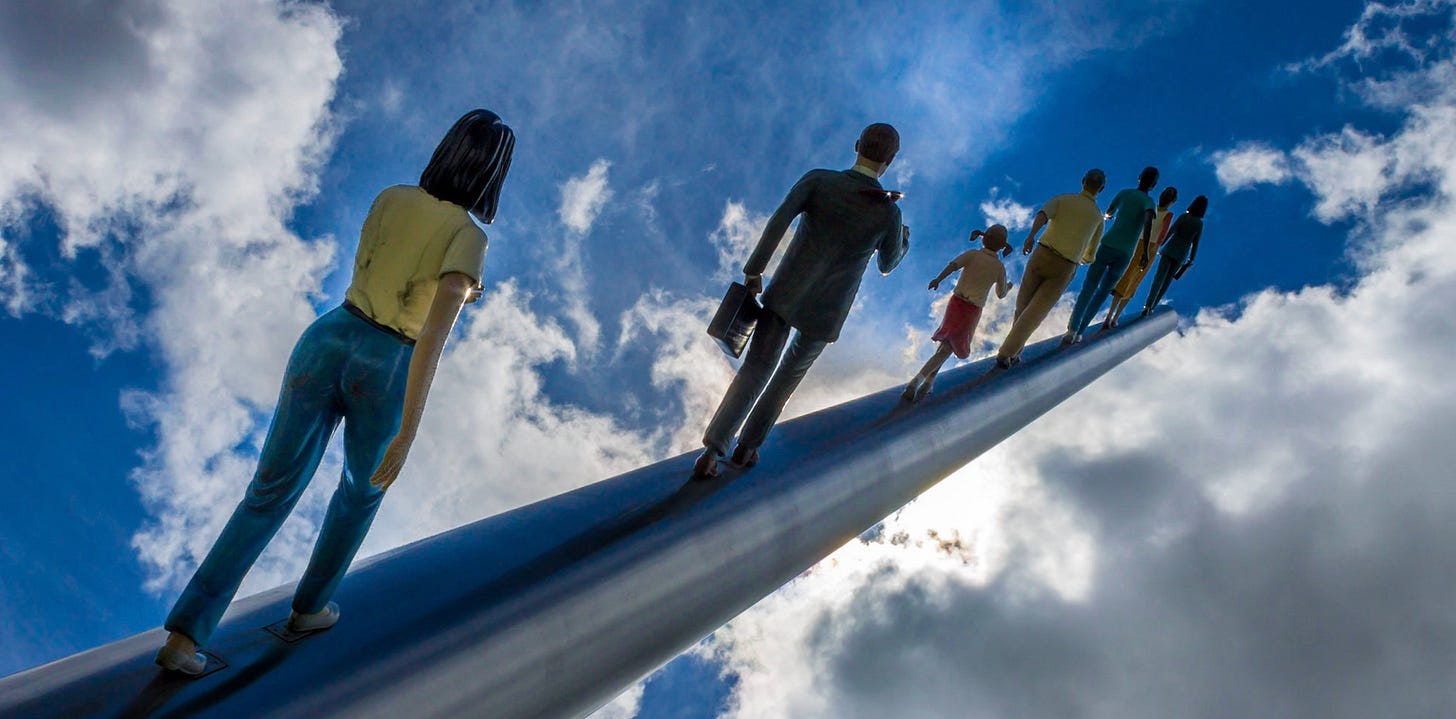 A statue of life-size human figures that appears as if they are walking along a pole into a blue sky with white clouds