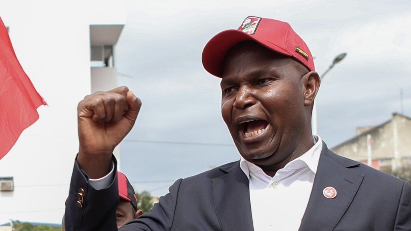 Daniel Chapo wearing a dark grey suit and red Frelimo cap with his fist raised at a campaign event at the China Mozambique Cultural Centre in Maputo - 2 October 2024