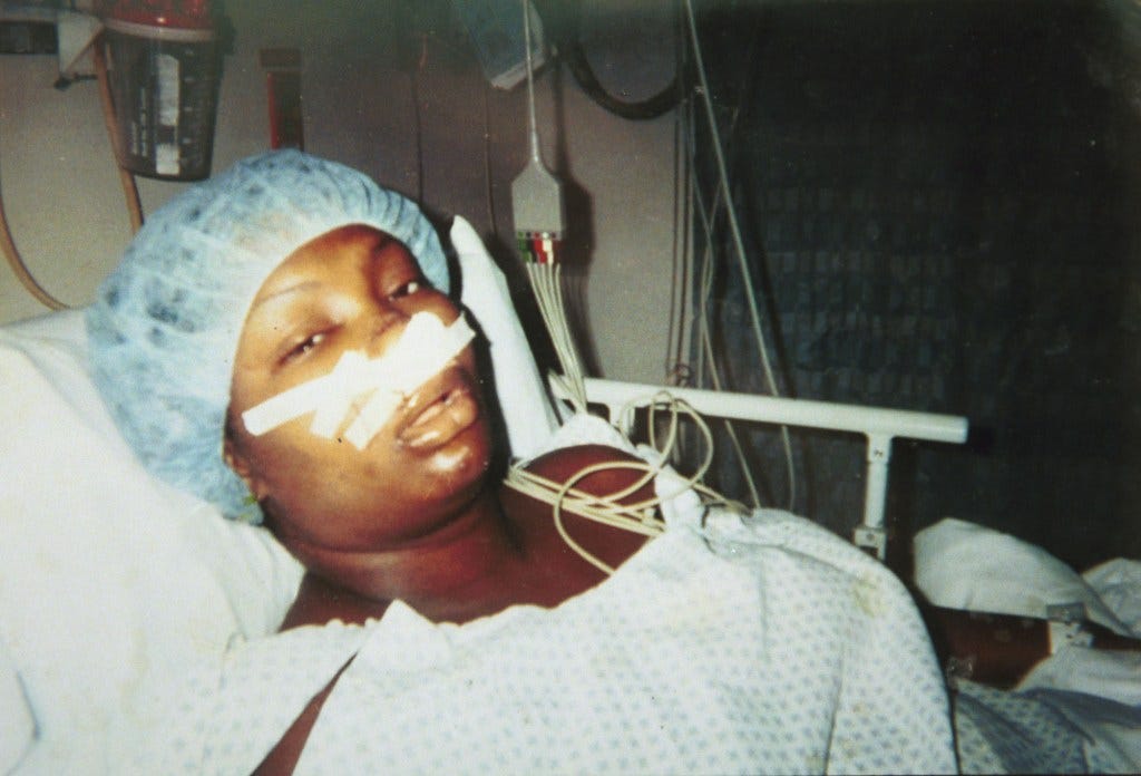 Natania Reuben in her hospital bed with her face bandaged after being shot at a club.