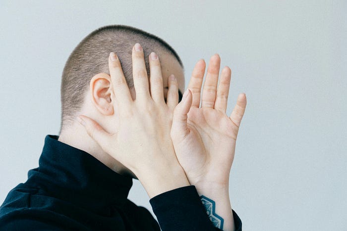 A person covering up their face with two hands so you can’t see anything