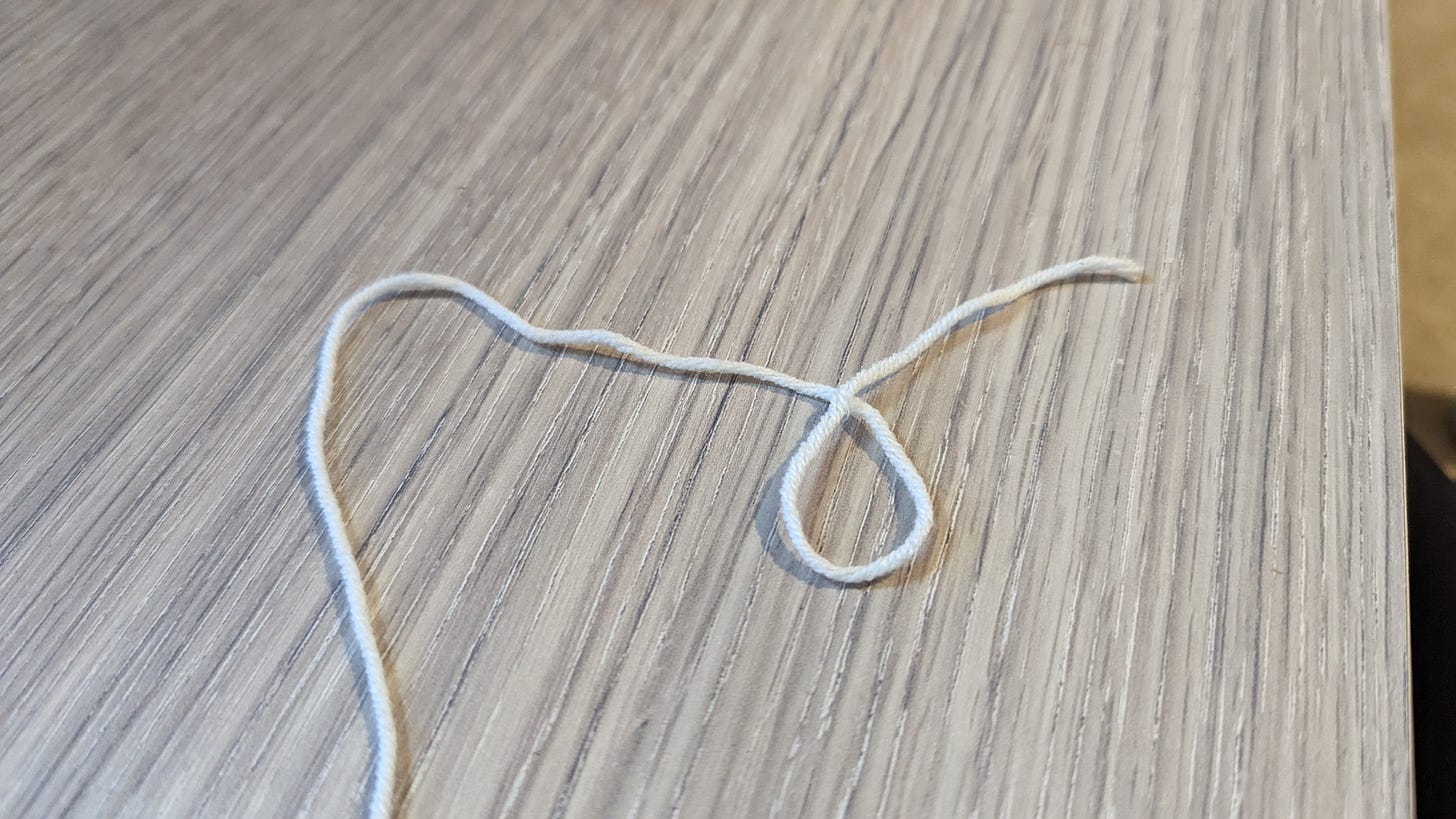 A string positioned in a loop, with the shorter end on top of the longer end