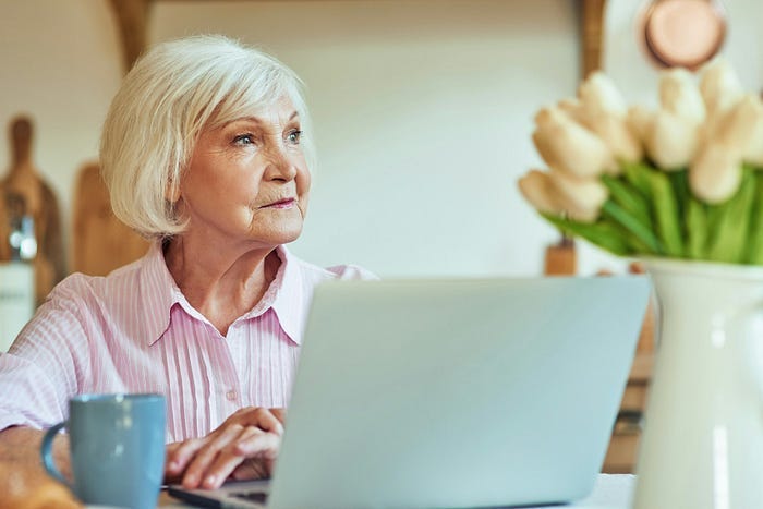 An older woman sitting at a computer.