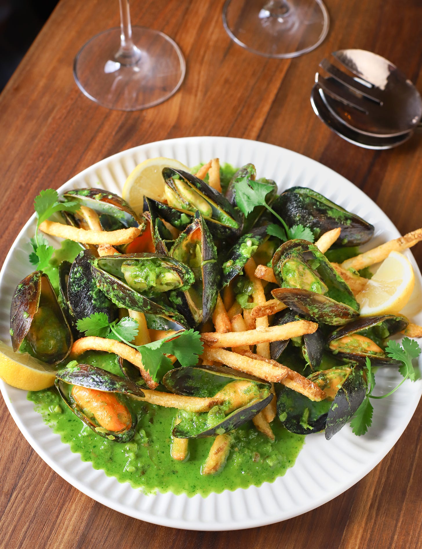 Plate with mussels in coconut-herb curry and French fries