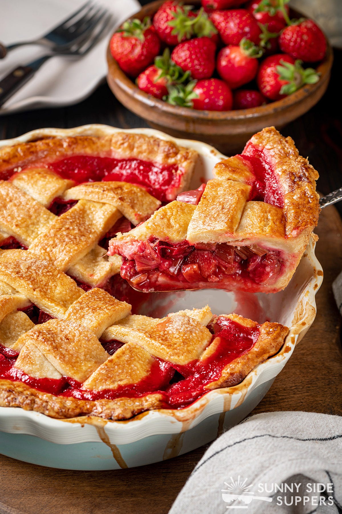 Slice of strawberry rhubarb pie being lifted out of a pan.