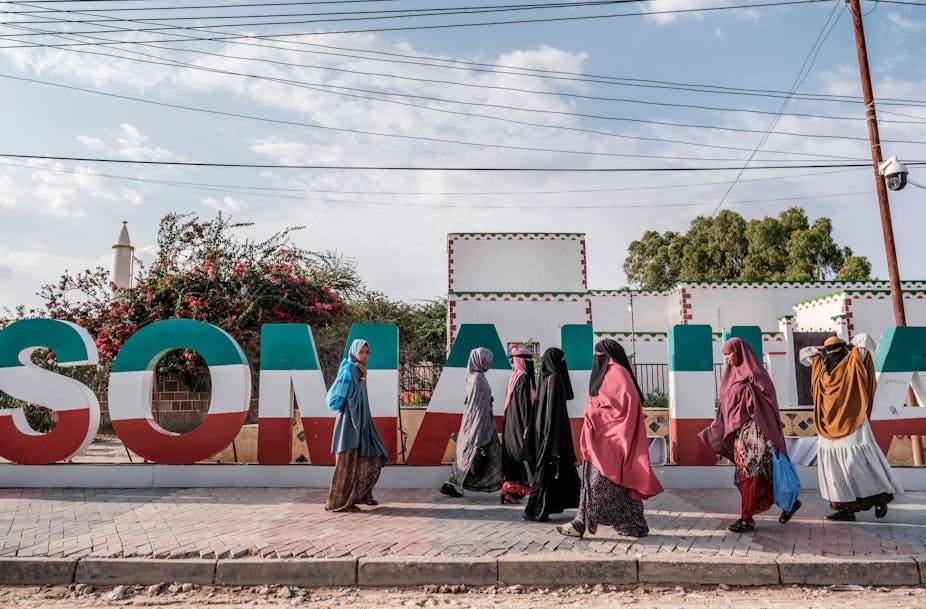 Women walking in front of Somaliland lettering in green, white and red