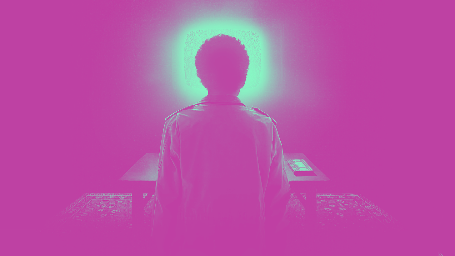 A promotional image of I Saw The TV Glow of a person, with their back to us, facing a glowing TV screen. The image has been processed to have only pink and cyan values, with cyan representing the highlights and pink representing the shadows of the image.