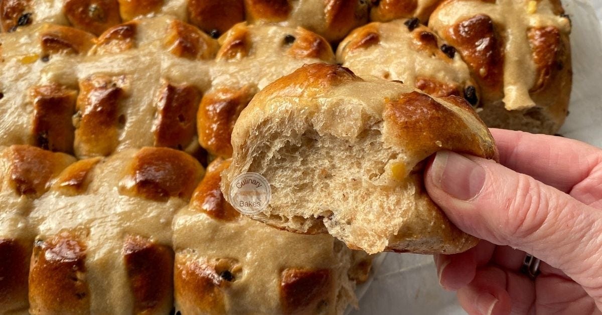 Hand holding a hot cross bun with fruit.