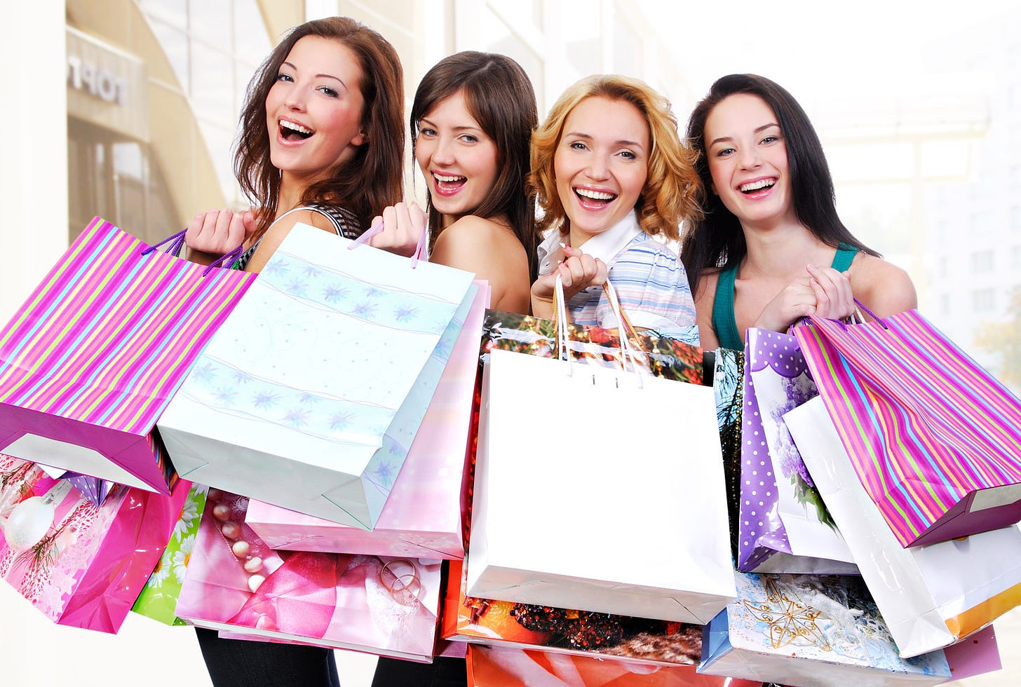 Four fakey, happy girls with their shopping bags from a spending spree
