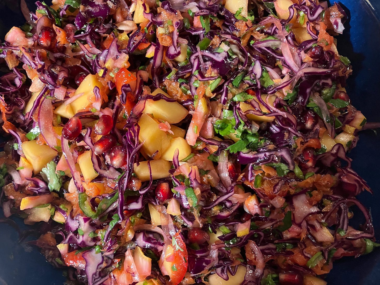 red cabbage salad with mango, lemon, and pomegranate seeds