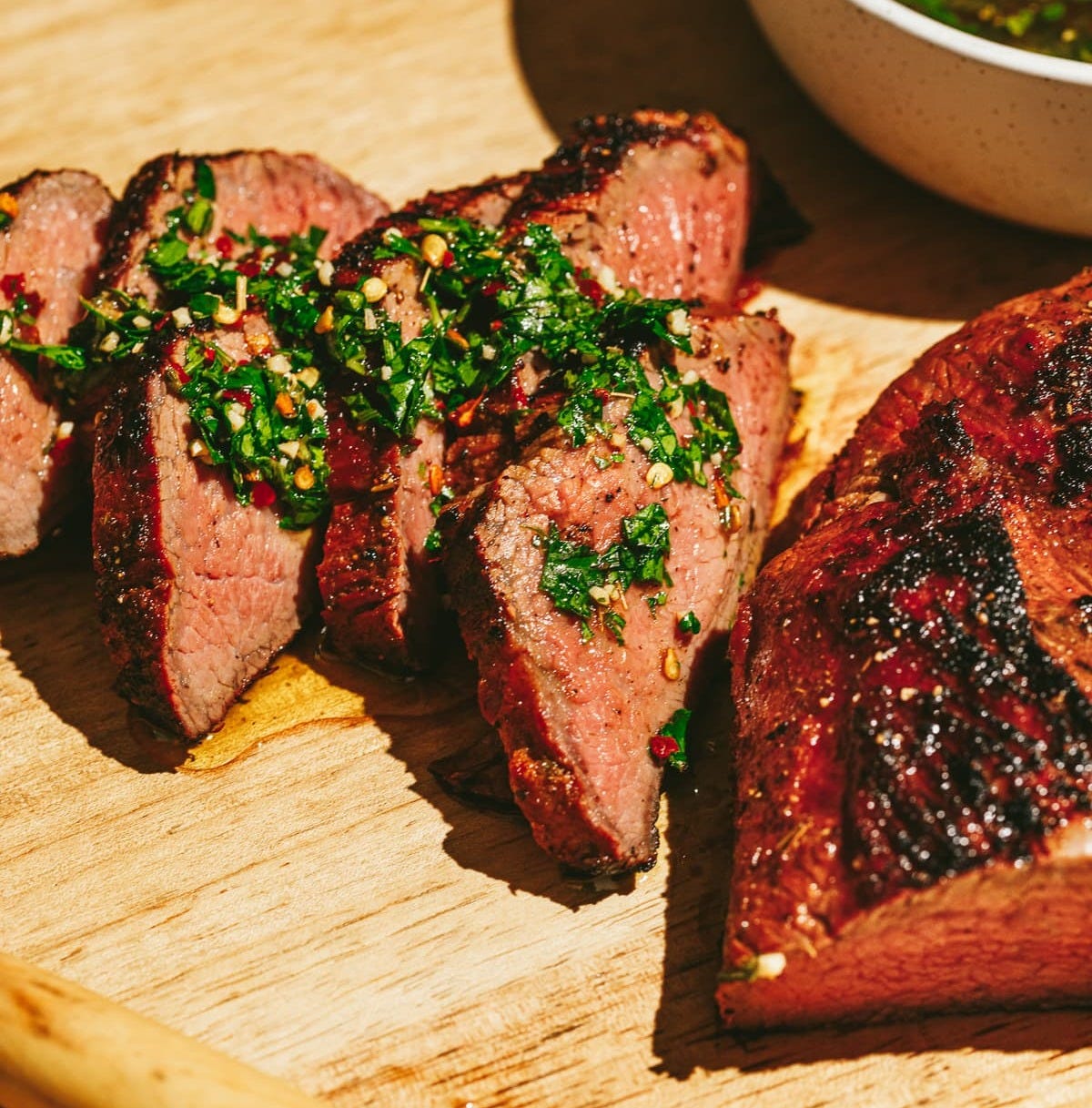 Trip tip with chimichurri on a cutting board.