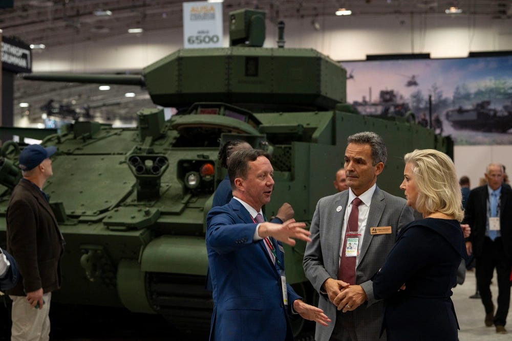 Secretary of the Army Hon. Christine Wormuth, looks on as an official with a defense contrator presents military equipment while on her floor walk during the 2024 Association of the U.S. Army Annual Meeting and Exposition