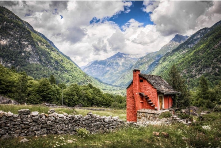 Red hut in front of rolling mountains
