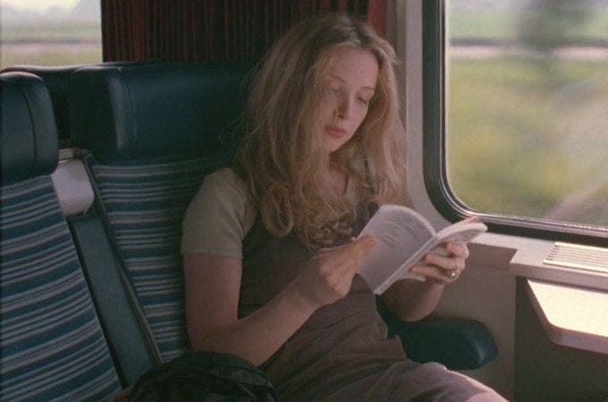 This may contain: a woman sitting on a train reading a book