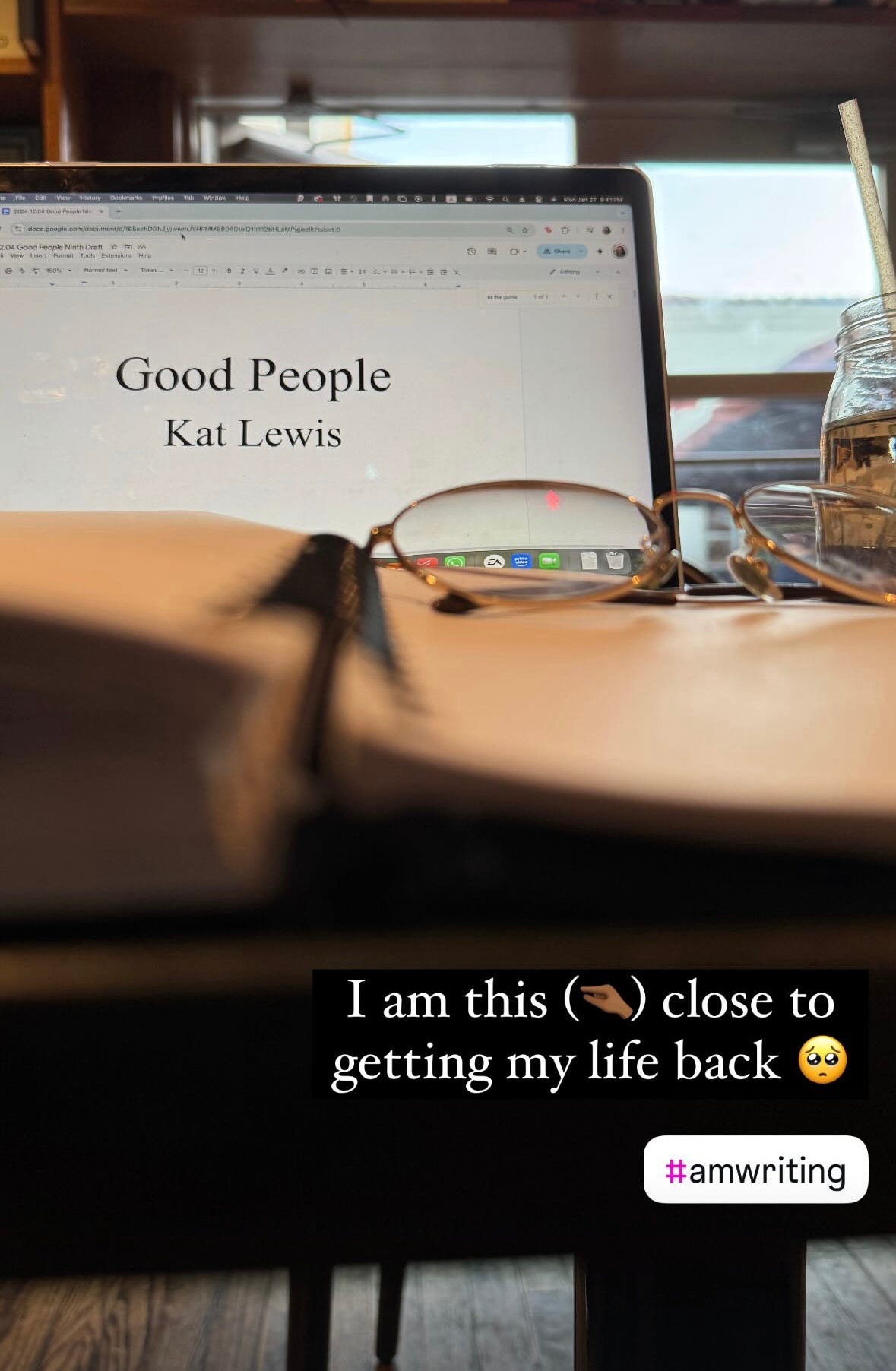 A photo of Kat’s printed manuscript opened to the 80% mark. In the background, her laptop screen displays the title page for her novel, GOOD PEOPLE.