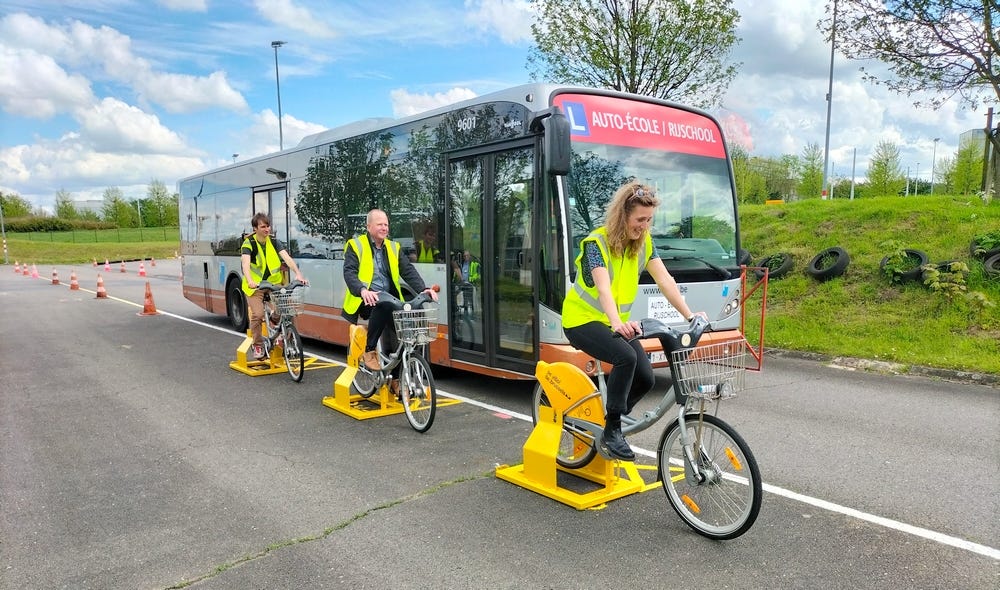 Trois chauffeurs de bus sur des velos se font froler par un bus, durant une formation.