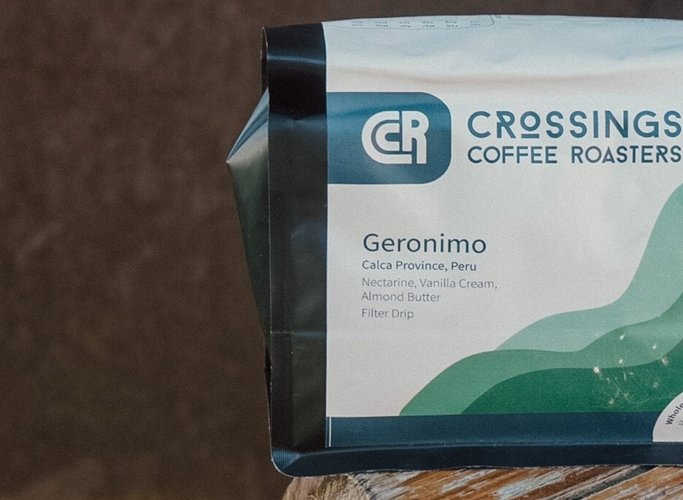 A close up of a black coffee bag with a white label featuring the Crossings Coffee Roasters typographic logo.